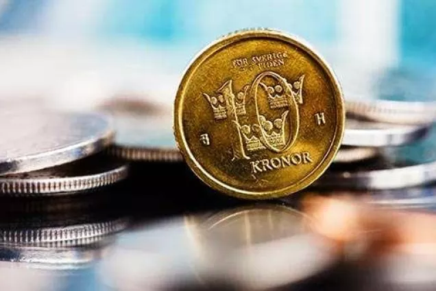 Fotografi på en tiokrona som står bland silvriga mynt