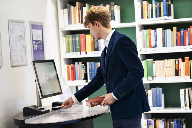 En student använder låneautomaten för att låna en bok. Foto.