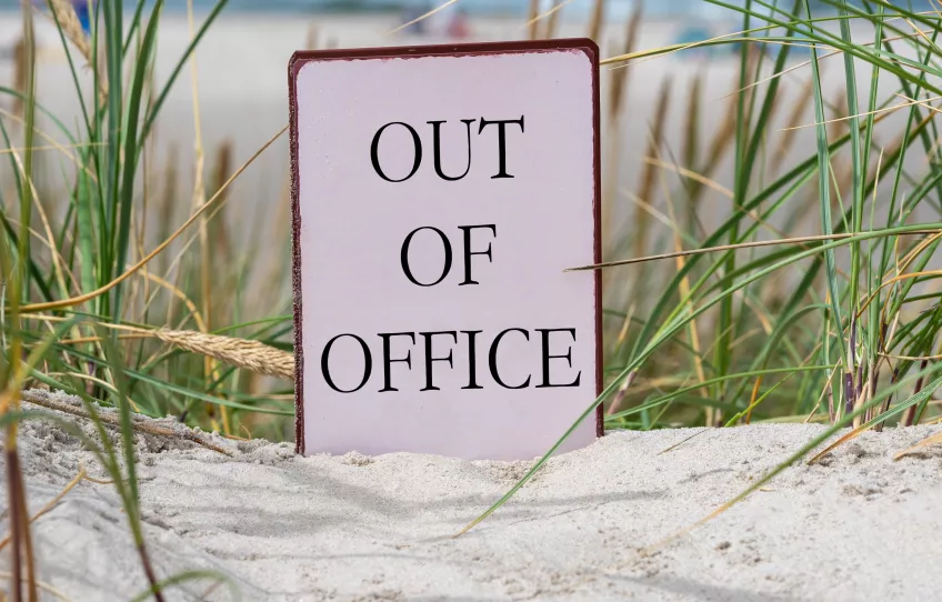 Photo of a sign standing on a sandy beach.